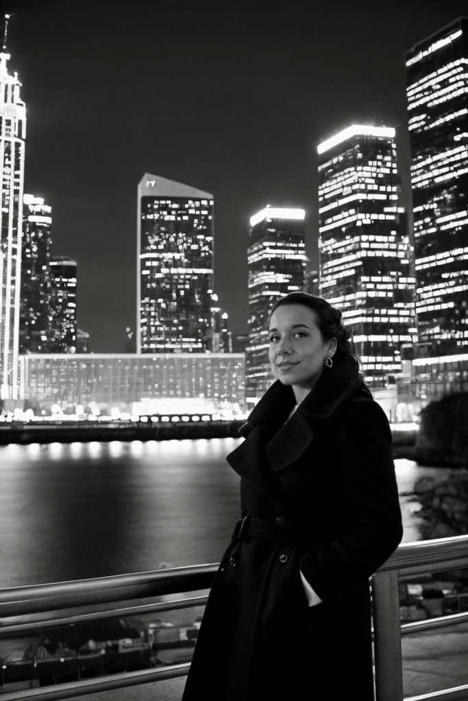 Create a scene of sophisticated city glamour with a woman wearing ohwx model lauraconfidently posing against an urban landscape. Utilize dramatic, directional lighting to add depth and contrast to the night scene. Capture the sleek silhouette of his long red coat with a low angle shot using a Leica camera. Enhance the mood with a black and white filter for added sophistication